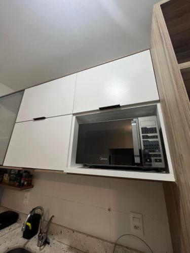 un microondas en un armario blanco en una cocina en Apartamento 2 Suítes com piscina e churrasqueira, ao lado da UFSC, en Florianópolis
