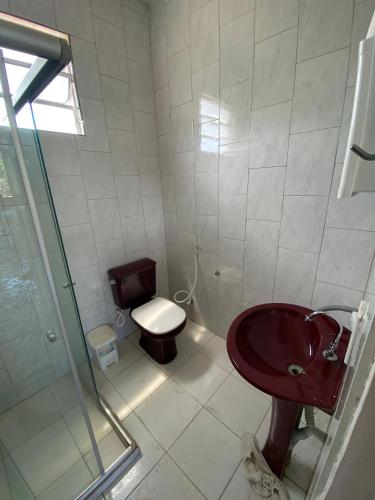 a bathroom with a red sink and a toilet at Sítio Curumim - Zohra in Itaparica