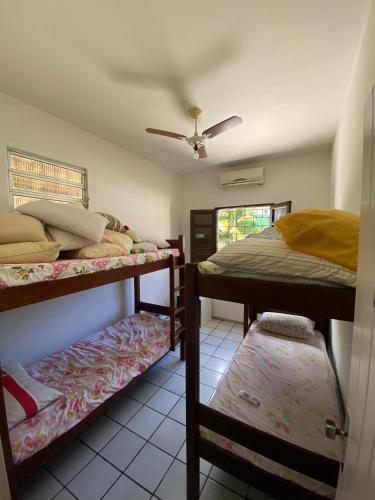 a bedroom with two bunk beds and a ceiling fan at Sítio Curumim - Zohra in Itaparica
