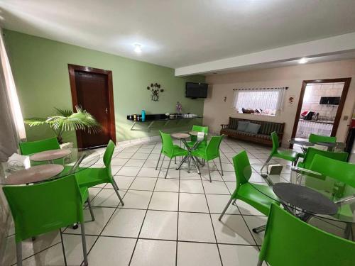 a dining room with green chairs and tables and a living room at Hotel Mirante in Inhaúma