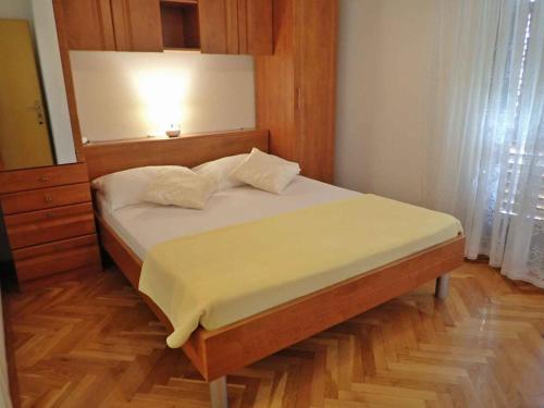 a bedroom with a bed with a wooden headboard at Apartments Seline/Paklenica Riviera 36550 in Seline