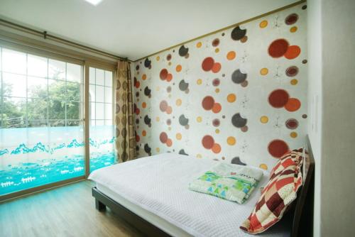 a bedroom with a bed and a wall with flowers at Sanbangsan Hot Spring Pension in Seogwipo