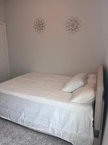 uma cama com lençóis brancos e almofadas num quarto em Home away from Home em Manvel