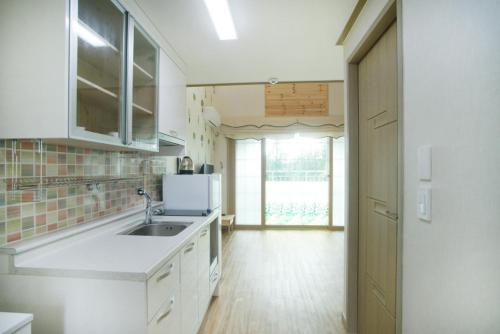 a kitchen with a sink and a refrigerator at Sanbangsan Hot Spring Pension in Seogwipo