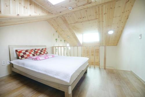 a bedroom with a bed in a room with wooden ceilings at Sanbangsan Hot Spring Pension in Seogwipo