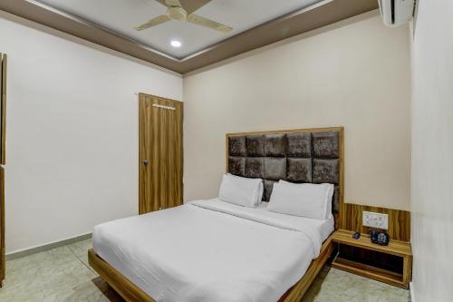 1 dormitorio con cama blanca y cabecero de madera en Capital O Hotel Maple View en Naroda