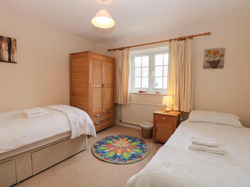 a bedroom with two beds and a dresser and a window at Sea Pearl in Lowestoft