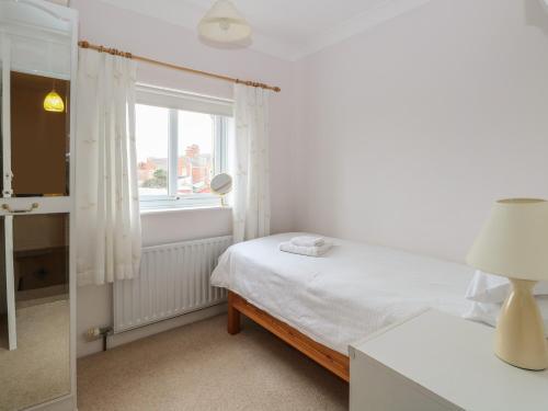 a white bedroom with a bed and a window at Sea Pearl in Lowestoft