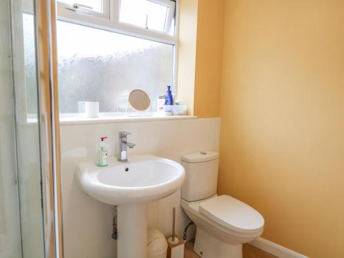 a bathroom with a toilet and a sink and a window at Sea Pearl in Lowestoft