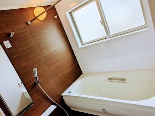 een badkamer met een witte wastafel en een raam bij 書斎でくつろぐスイートルーム in Nagoya