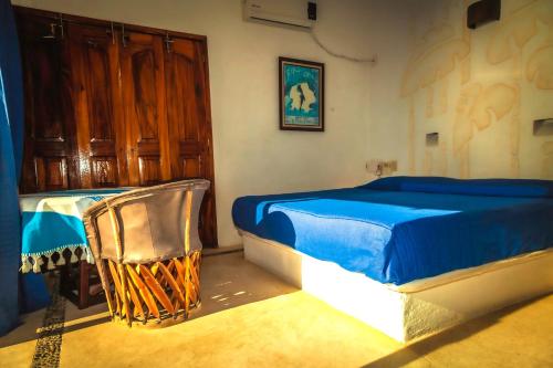 a bedroom with a blue bed and a chair at Villas Mykonos in Zipolite