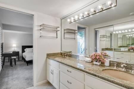 La salle de bains est pourvue d'un lavabo et d'un grand miroir. dans l'établissement West Irving Palace Miami Style, à Irving
