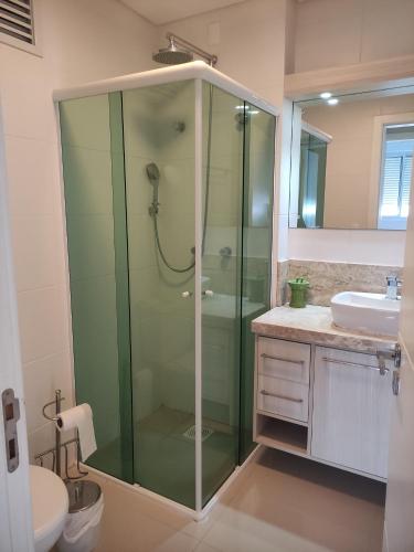 La salle de bains est pourvue d'une douche en verre et d'un lavabo. dans l'établissement Apartamento em Canasvieiras, à Florianópolis