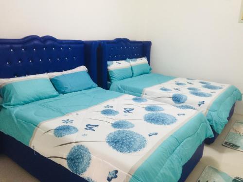 um quarto com 2 camas com lençóis azuis e brancos em MGH Space Rental 