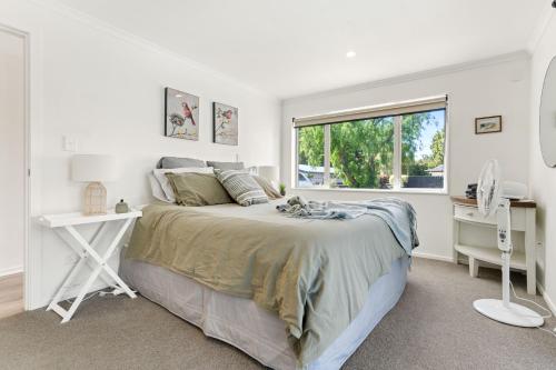 a white bedroom with a bed and a window at High Street Pool House in Masterton
