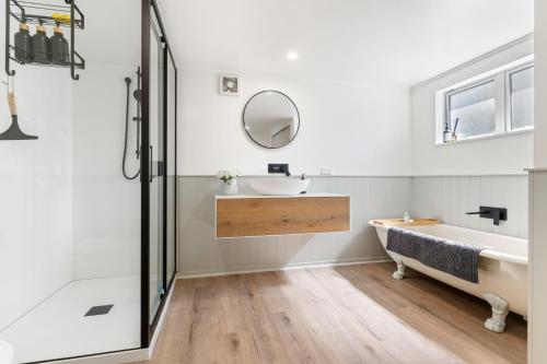 a bathroom with a tub and a sink and a mirror at High Street Pool House in Masterton
