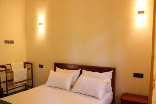 a bedroom with a bed with white pillows at Palm & Wild Hiriketiya in Dickwella