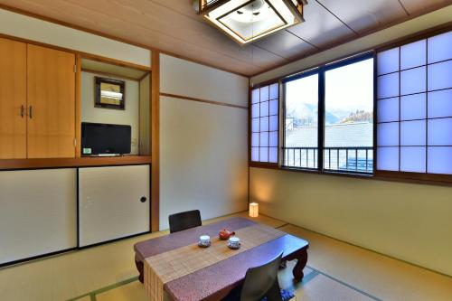 a dining room with a table and two windows at 万葉茶寮みさか in Hirugami