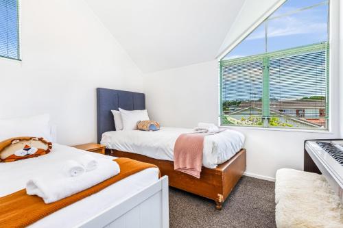 Duas camas num quarto com uma janela em Private and sunny 3-bedroom home with parking em Auckland