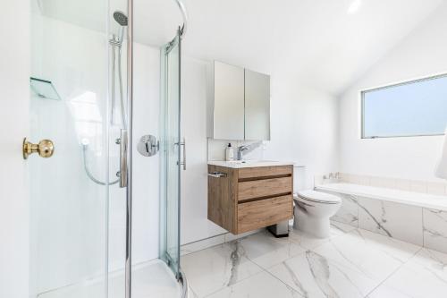 uma casa de banho com um chuveiro, um lavatório e um WC. em Private and sunny 3-bedroom home with parking em Auckland