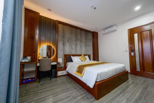 a bedroom with a bed and a desk and a mirror at MIMOSA HOTEL in Ha Long
