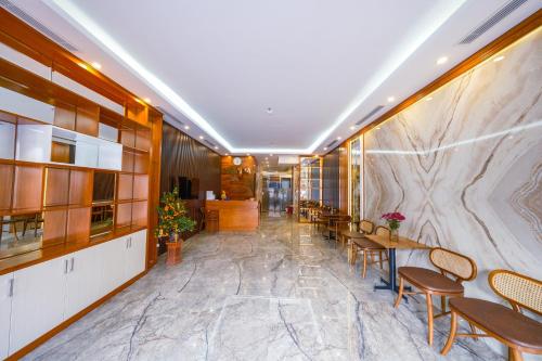 eine Lobby mit Tischen und Stühlen und einer Marmorwand in der Unterkunft MIMOSA HOTEL in Hạ Long