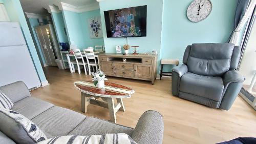 Sunkissed-Modern Oceanfront Condo Daytona Beach في دايتونا بيتش: غرفة معيشة مع أريكة وطاولة وكراسي
