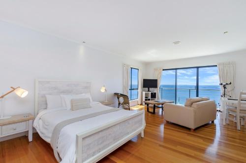 ein Schlafzimmer mit einem großen weißen Bett und einem Stuhl in der Unterkunft Clifftop Apartments Portland Vic in Portland