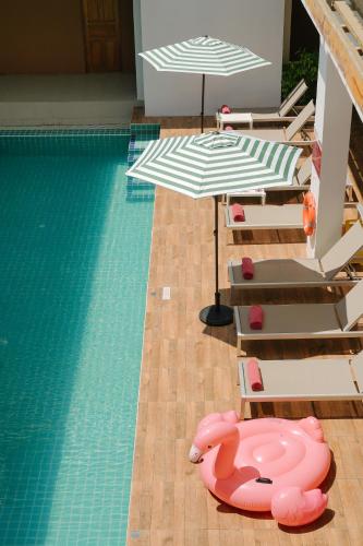 a swimming pool with lounge chairs and umbrellas and a swimming pool at Nonnee Hotel Kata Beach Phuket in Kata Beach