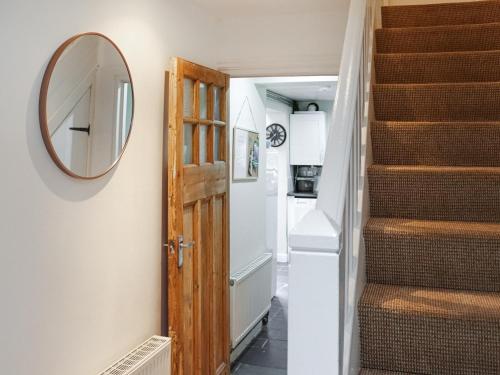 a hallway with a mirror and stairs in a tiny house at Maes Derlwyn in Llanberis