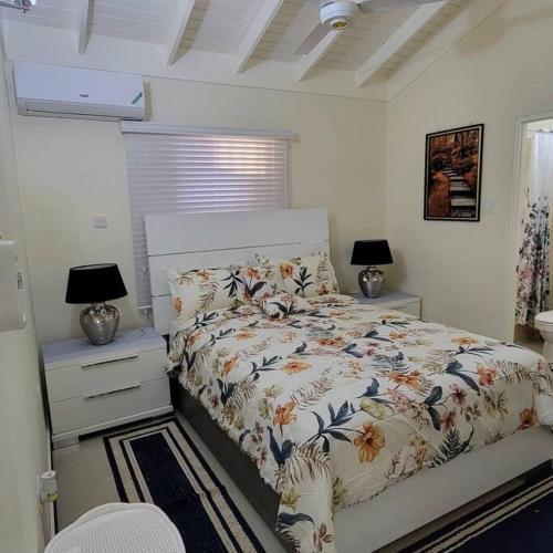 a bedroom with a bed and two night stands and two lamps at Home Away From Home in Old Harbour