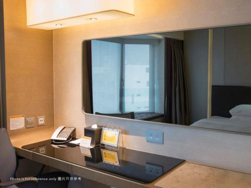 a mirror in a hotel room with a phone at Royal Plaza Hotel in Hong Kong