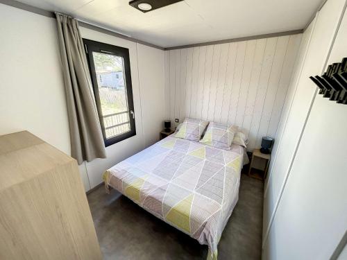 une petite chambre avec un lit et une fenêtre dans l'établissement Chalet à Jullouville - 6 couchages, piscine chauffée, près de la plage et commerces - FR-1-361-523, à Jullouville