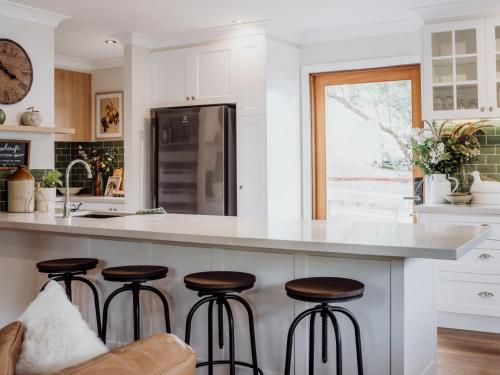 a kitchen with white cabinets and bar stools at Mountview Alpaca Farmhouse in Canungra