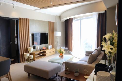 ein Wohnzimmer mit einem Sofa und einem TV in der Unterkunft AEON SUITES STAYCATION managed by ARIA HOTEL in Davao City
