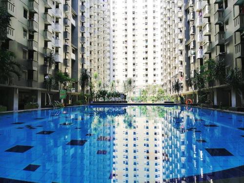 een groot blauw zwembad met hoge gebouwen bij Blossom Suites Bandung Cicadas at Gateway Apartment in Bandung