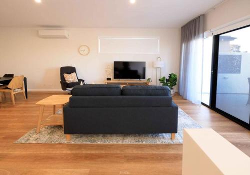 a living room with a black couch and a table at Neddidge Apartment 3 in Albury