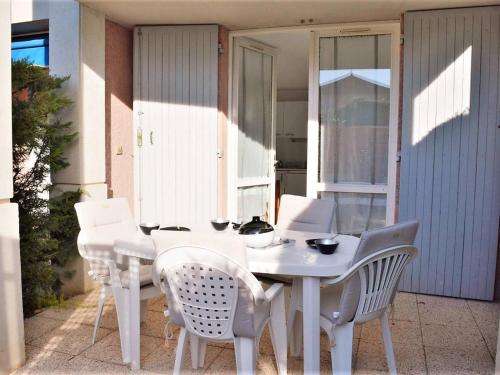 une table blanche et des chaises sur une terrasse dans l'établissement Studio cabine climatisé avec terrasse, 2 pas de la plage, 4 couchages, ménage inclus - Cavalière - FR-1-251-554, au Lavandou