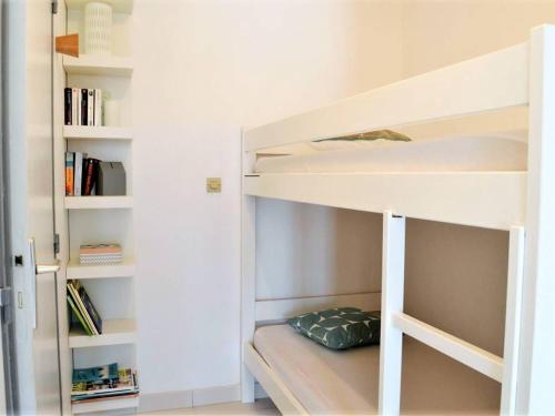 Ce lit superposé blanc se trouve dans un dortoir doté d'étagères. dans l'établissement Studio cabine climatisé avec terrasse, 2 pas de la plage, 4 couchages, ménage inclus - Cavalière - FR-1-251-554, au Lavandou