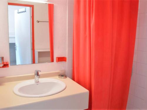 La salle de bains est pourvue d'un lavabo et d'un rideau de douche rouge. dans l'établissement Studio cabine climatisé avec terrasse, 2 pas de la plage, 4 couchages, ménage inclus - Cavalière - FR-1-251-554, au Lavandou