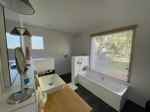 une salle de bain avec une baignoire, un lavabo et un miroir dans l'établissement Villa avec piscine, 10 pers, au calme, climatisée, terrasse, grand jardin - FR-1-379-169, à Soustons