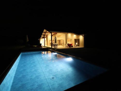 - une piscine avec une maison la nuit dans l'établissement Villa avec piscine, 10 pers, au calme, climatisée, terrasse, grand jardin - FR-1-379-169, à Soustons