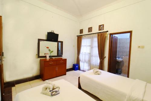 a hotel room with two beds and a television at Sinergi Hotel Tretes in Pasuruan