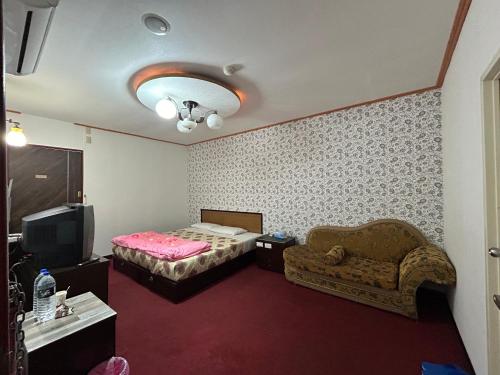 a bedroom with a bed and a couch and a tv at 林中林民宿 in Chien-shan