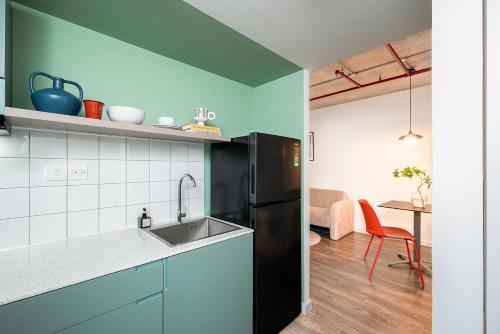 a kitchen with a sink and a black refrigerator at M Village Kỳ Đồng in Ho Chi Minh City