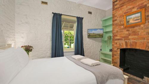 um quarto com uma cama branca e uma lareira em Loch Lomond Lodge em Mittagong