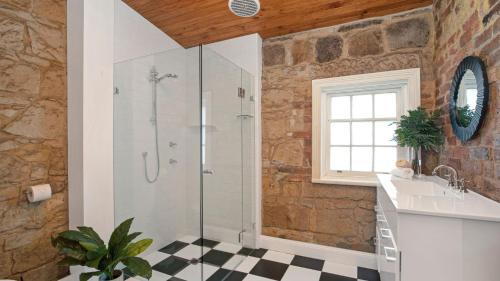 uma casa de banho com um chuveiro e um lavatório. em Loch Lomond Lodge em Mittagong