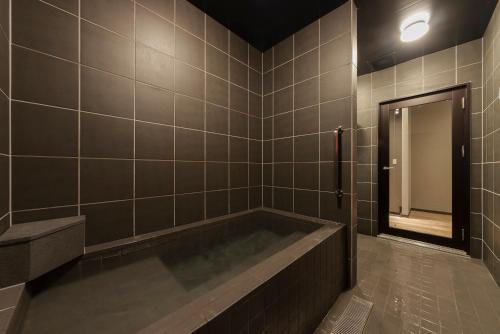 a bathroom with a bath tub and a mirror at BEPPU ROJIURA stay&sauna in Beppu