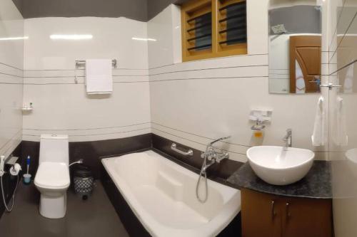 a bathroom with a tub and a sink and a toilet at Casa Royal HomeStay in Kattappana