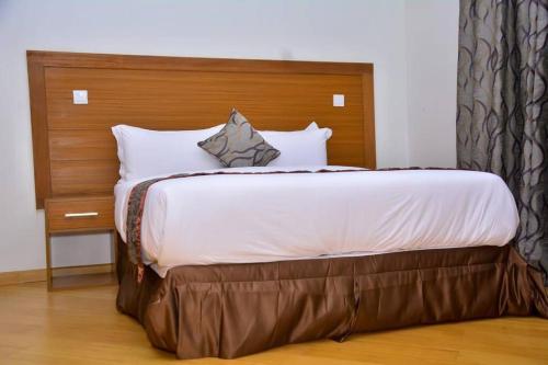 a bedroom with a large bed with a wooden headboard at Relax on the high-end space in Nairobi
